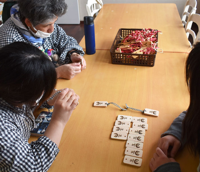 TOP JIMMY オリジナルウッドチャーム Cafeあすなろの障がいをもつスタッフがパラコードの仕上げを作業する風景